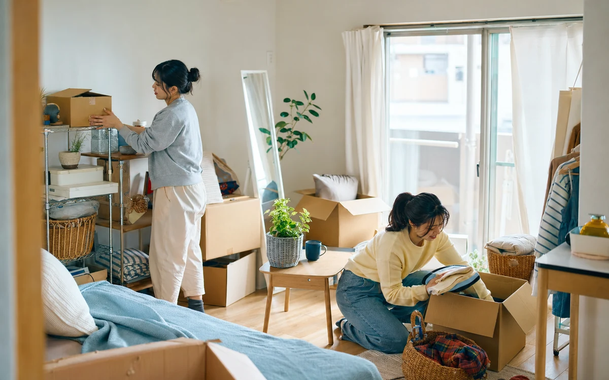 밝은 일본 원룸에서 이삿짐을 함께 정리하는 청년 두 명